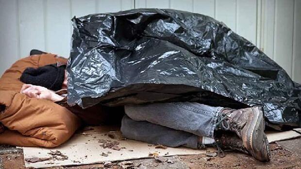 A person sleeping outdoors under a tarp, from CBC's coverage of a study on mental illness among Calgary's homeless population.